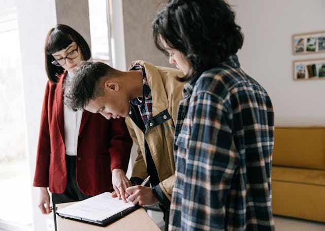 A guy signing document beside two girls
